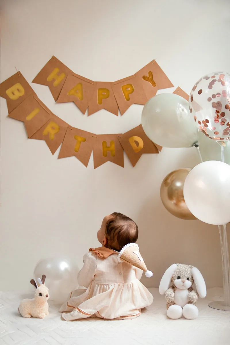 Toddler seen from behind beside soft toys and balloons