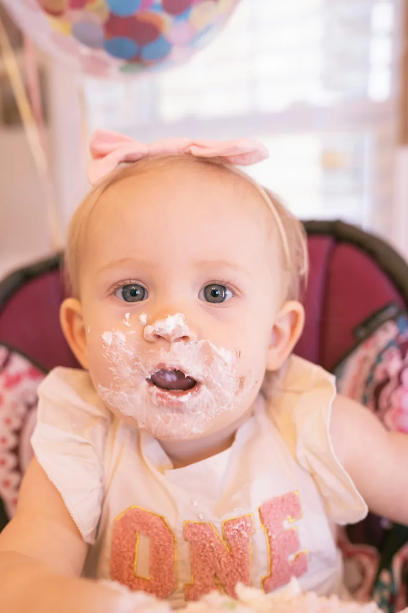 Baby with frosting on their face during a first birthday cake smash