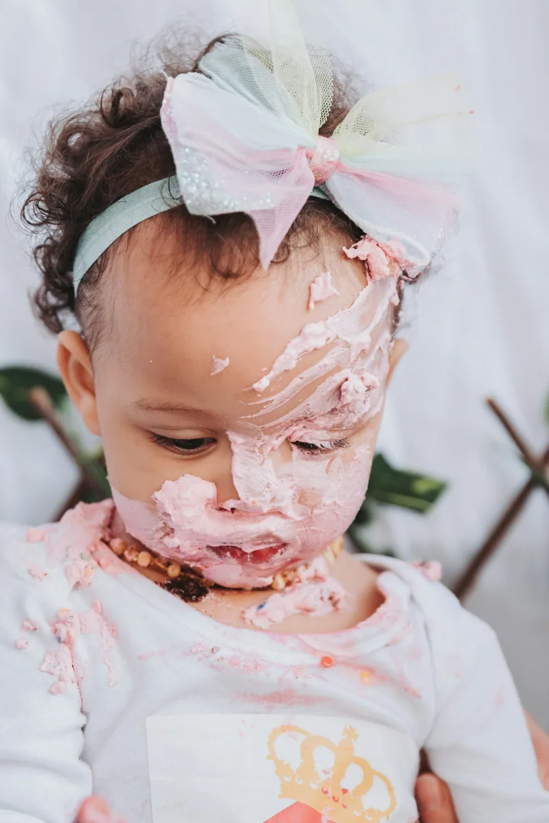 Toddler in a pastel bow after a cake smash session