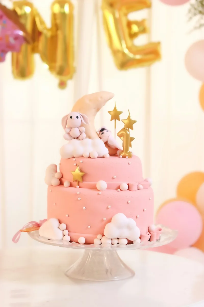 Pink birthday cake with a bunny topper and gold stars
