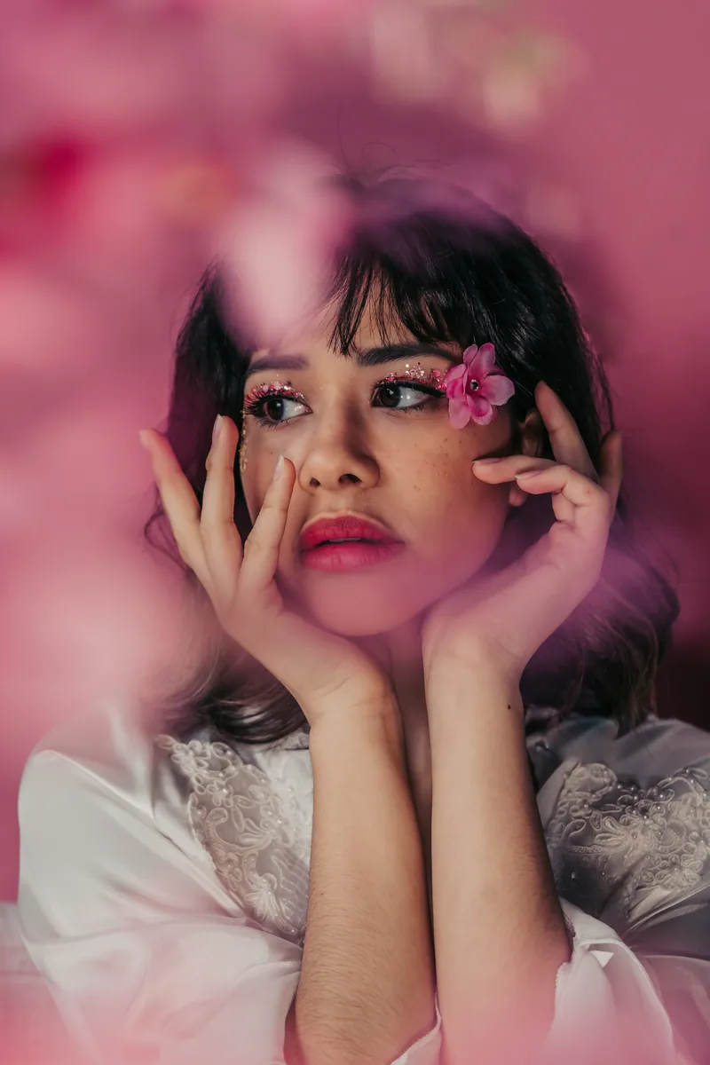 Portrait framed by soft pink blossoms, a flower tucked behind her ear