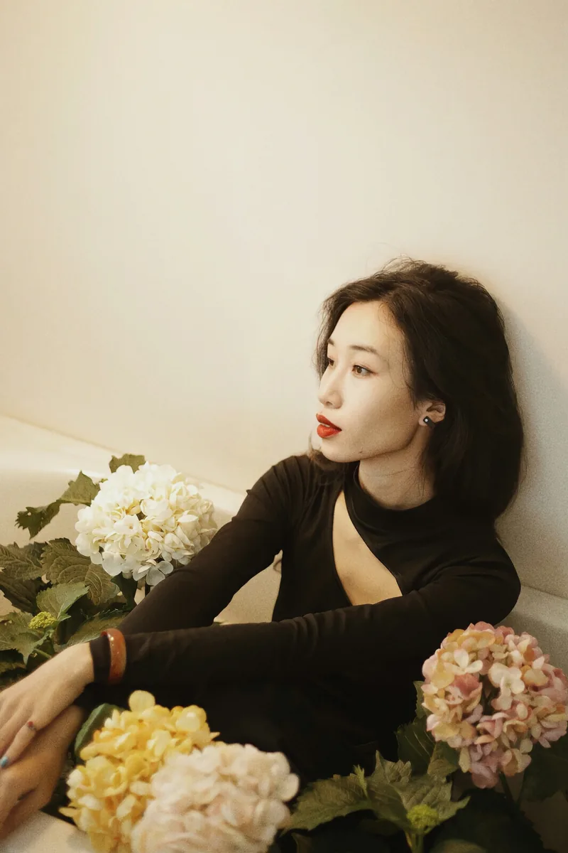 Woman in black seated among cream and yellow hydrangeas